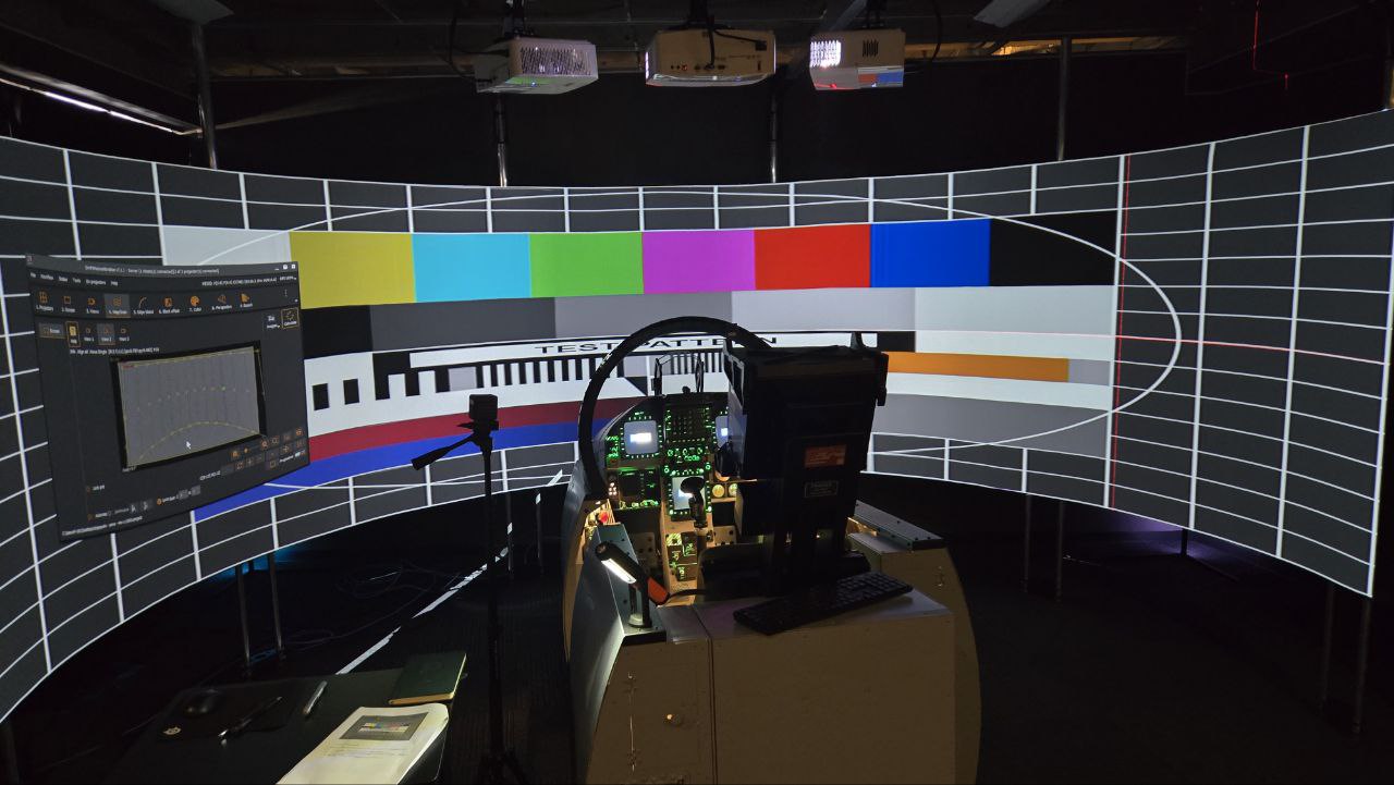 Full colour-bar calibration test pattern projected across a SimPit curved surface, with the Warp calibration software visible on screen